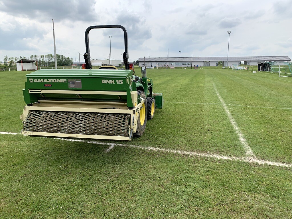 Entretien mécanique d’un terrain de sport avec tracteur John Deere et matériel Amazone